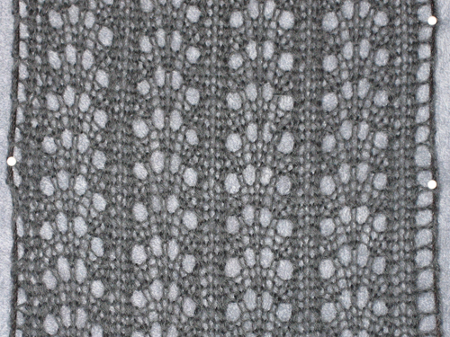 Close up of blocking scarf with yarn holding the edges taut