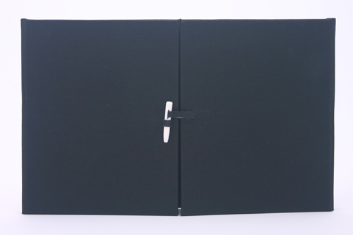 Black gate-fold book fastened closed with bone clasp