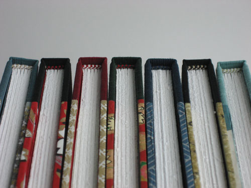 The heads of seven brightly decorated books, with hand-sewn two-color endbands