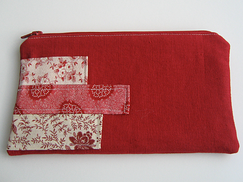 Red linen pencil case with strips of red and white floral quilting fabric