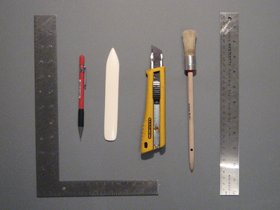 Carpenter's square, pencil, bone folder, utility knife, paste brush, and steel ruler