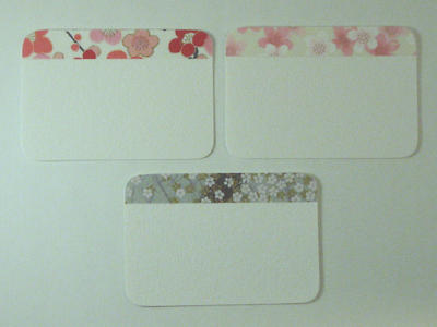 Several gift cards with strips of decorative paper glued to the top