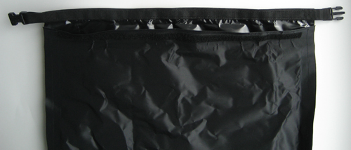 A close up view of the top of the dry bag, showing the webbing, buckle and velcro that hold the flap closed.