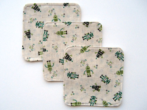 Three square coasters made from linen fabric screen printed with green and brown robots.