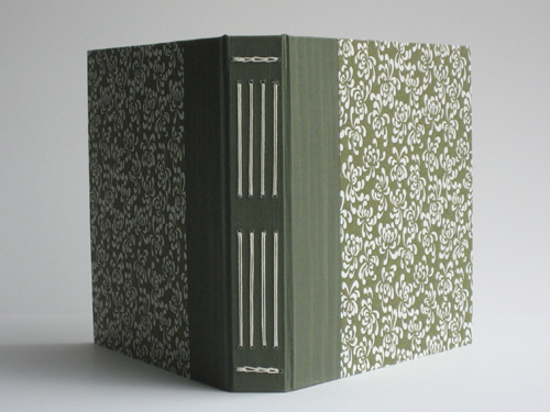 The book is fanned open and shot from the back, showing the spine detail as well as how the bookcloth wraps around and meets the decorative paper on the front.