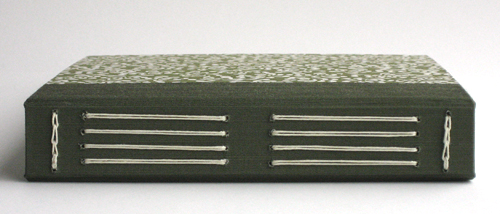 Cream colored thread sewn in four sets of parallel vertical stitches running most of the height of the book, with a row of horizontal link stitches at the top and bottom.