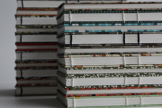 Two stacks of Coptic-bound books, angled to show the stitching detail on the spine