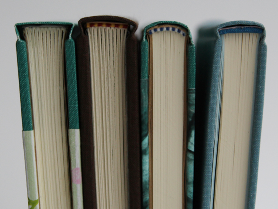 Four books lined up and showing the top edges